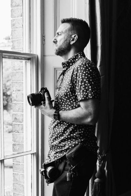 Tony from Tony Davies Weddings by a window with his camera